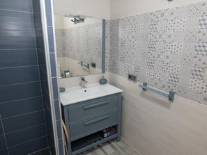 Une salle de bain avec un lavabo blanc, un miroir et des carreaux à motifs.