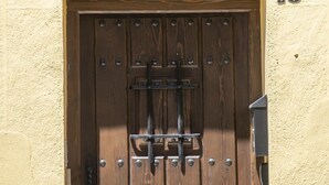 Une porte en bois, dotée d’un loquet métallique et d’une plaque au-dessus portant l’inscription « CAESARINA 15 ».