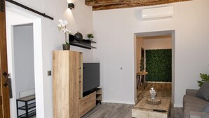 Un salon moderne avec un meuble de rangement en bois, un téléviseur à écran plat, une table basse et un mur vert.