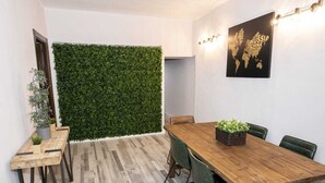 Un espace repas avec une table et des chaises en bois, un mur vert et une œuvre d’art représentant une carte.