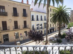 Une vue de rue avec des bâtiments, un palmier et des tables à l’extérieur.