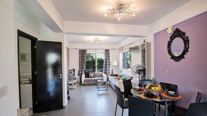 Un soggiorno moderno con zona pranzo, una porta nera e una parete viola con uno specchio.