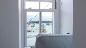 A room with a large window overlooking a harbor with boats and a bridge.