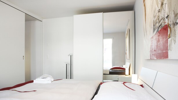 Ein modernes Hotelzimmer mit einem Bett, einem Spiegel und einem Bild an der Wand.