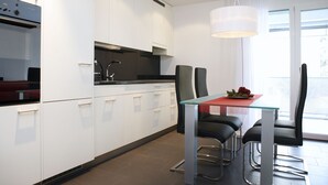 Eine moderne Küche mit weißen Schränken, einem Glastisch und schwarzen Stühlen.