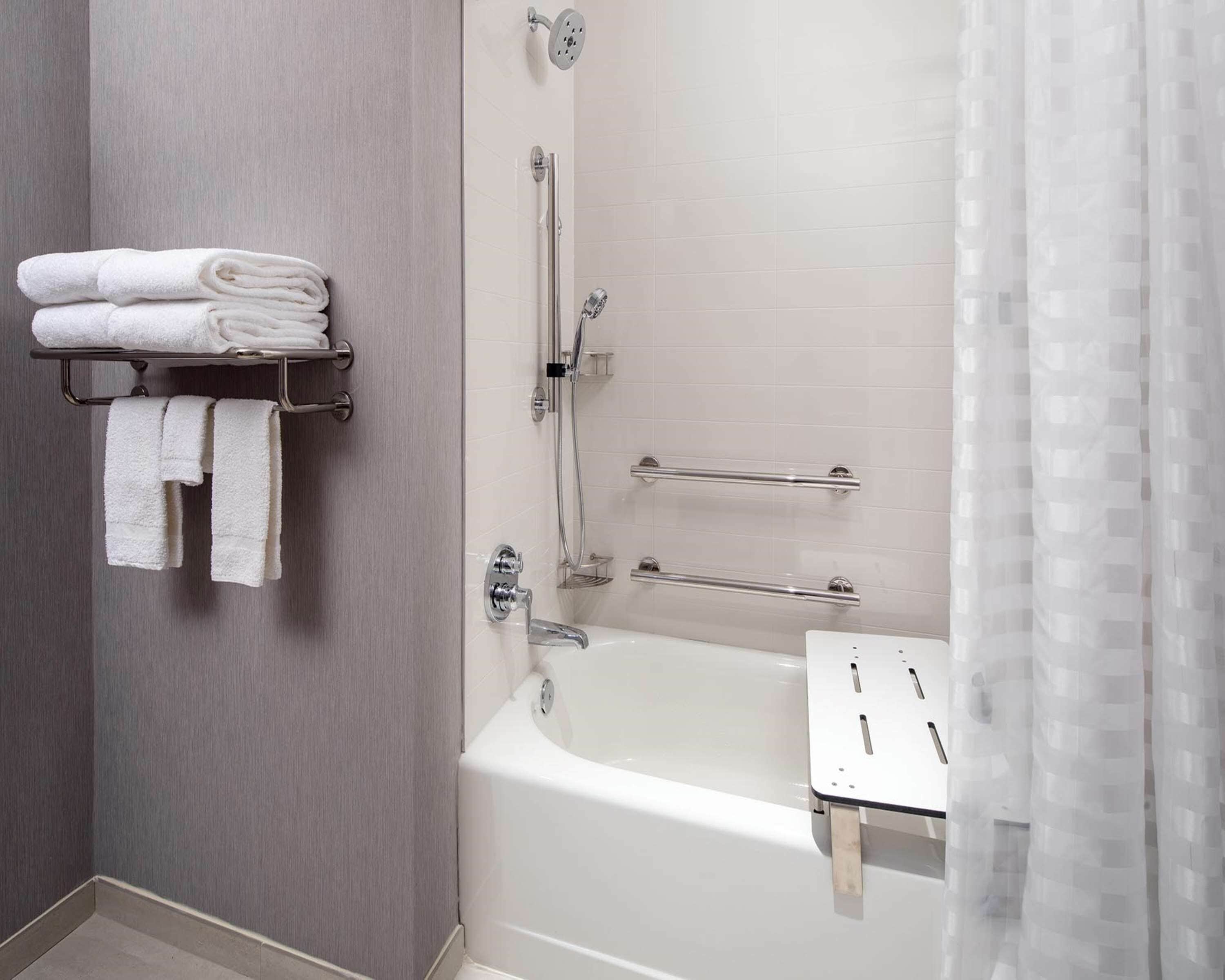 A modern bathroom with a bathtub, a shower, and a towel rack with folded towels.