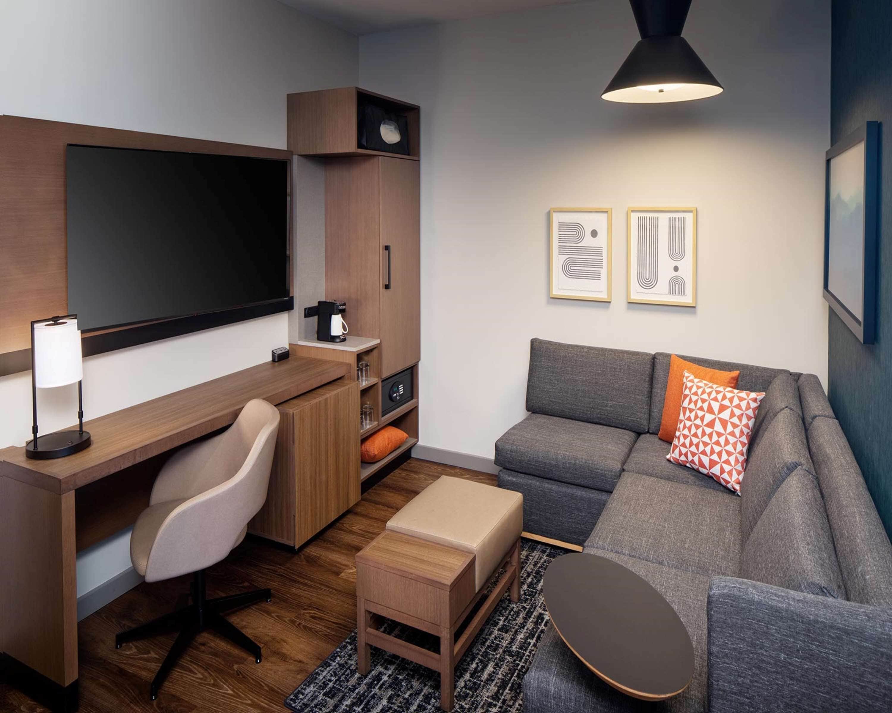 Un espace de vie moderne et compact, comprenant un bureau, une chaise, un canapé et une machine à café.