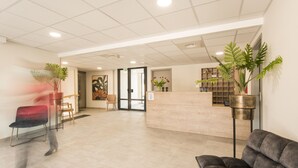 Un espace d’accueil comprenant un comptoir de réception, des sièges et des plantes en pot.