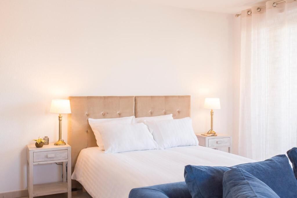 Een keurig opgemaakt slaapkamer met een bed, twee nachtkastjes en een bedbank.