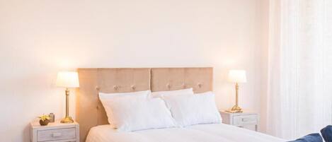 Un dormitorio ordenado con una cama, dos mesitas de noche y un tocador.