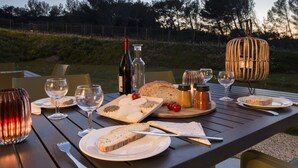 Une table en bois, dressée pour un repas, avec des assiettes, du pain, du fromage et des verres à vin.