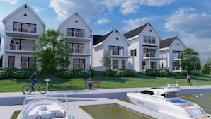 Un complejo residencial moderno con varias casas de dos pisos, un puerto deportivo con barcos y un césped bien cuidado.