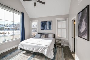 Un dormitorio con una cama grande, un ventilador de techo y vistas a un paisaje nevado por la ventana.