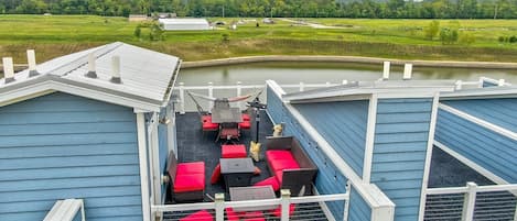 A covered outdoor deck with seating and a view of a green landscape.