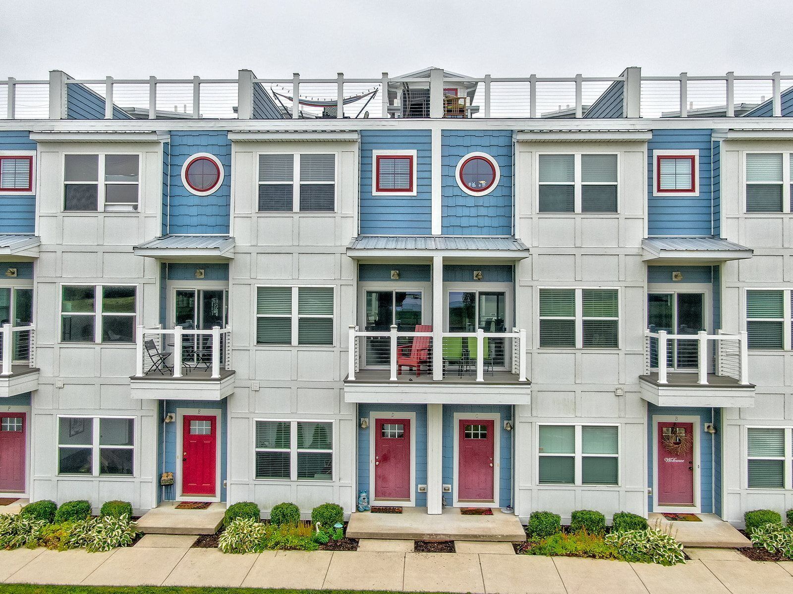A row of townhouses with multiple balconies, each with a small porch and a red door.