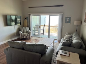 Relax in this stylish living room with a large sofa, armchair, and flat-screen TV.