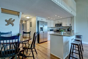 Enjoy cooking in this well-equipped kitchen with a refrigerator, microwave, and oven, as well as a dining area with a table and chairs.