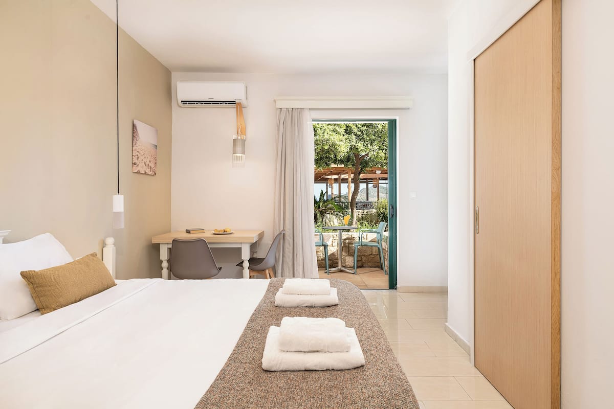 A hotel room with a bed, a desk, a chair, and a view of the outdoors.