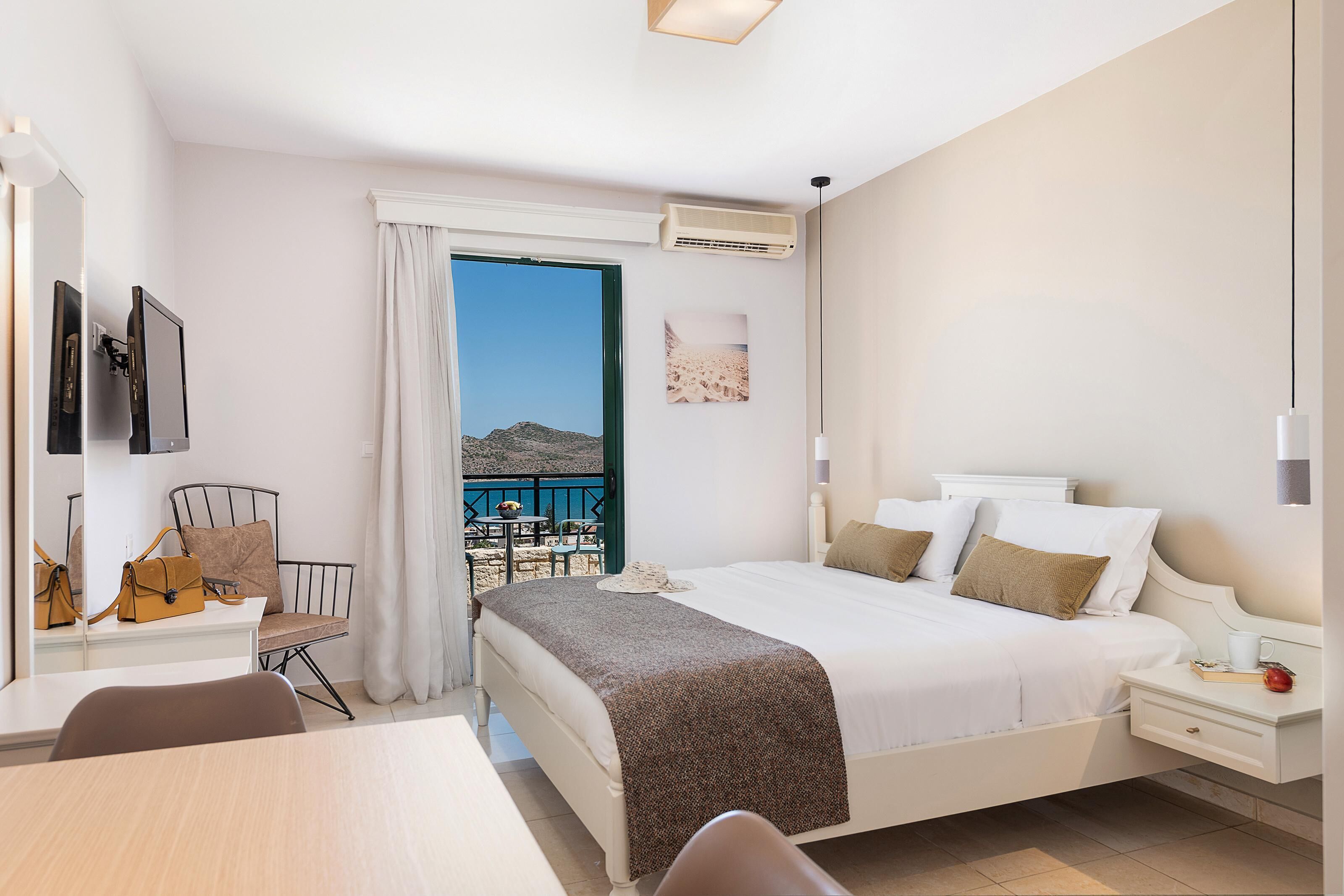 Une chambre d’hôtel équipée d’un lit, d’un bureau, d’une chaise, d’un balcon avec vue et d’un appareil de climatisation.