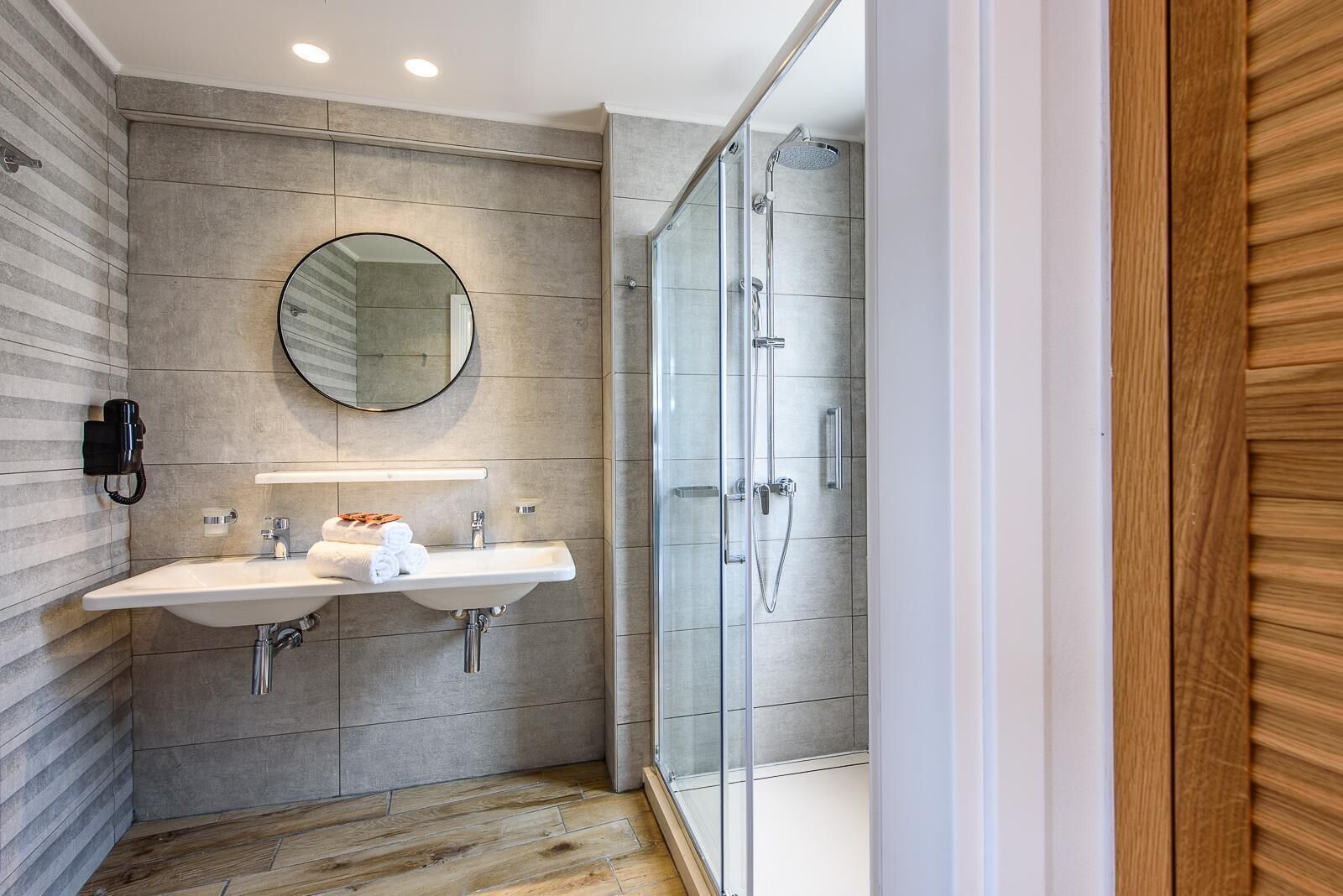 A modern bathroom with two sinks, a mirror, and a glass-enclosed shower.