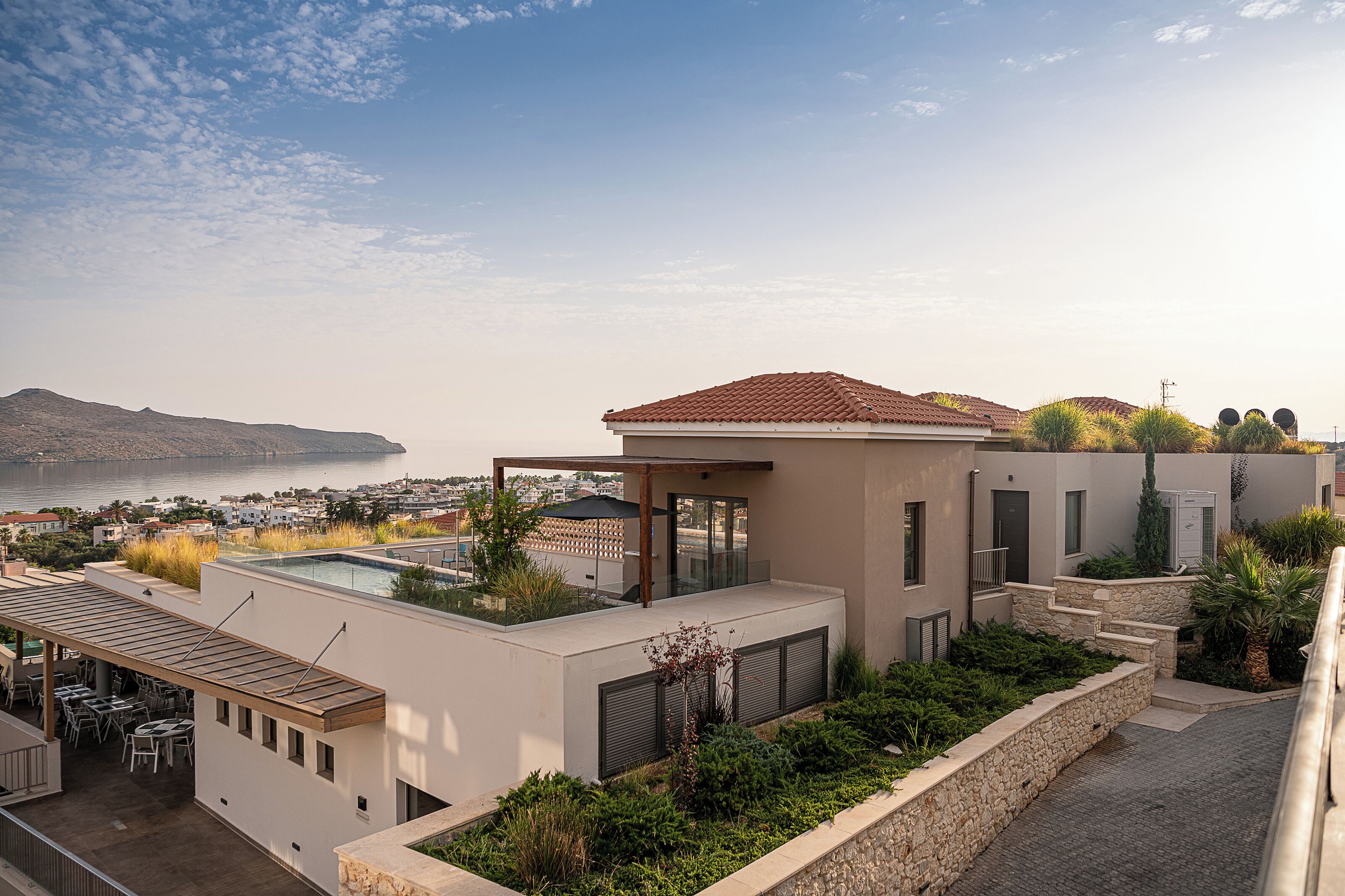 Un edificio moderno con patio sul tetto, piscina e vista sul mare.