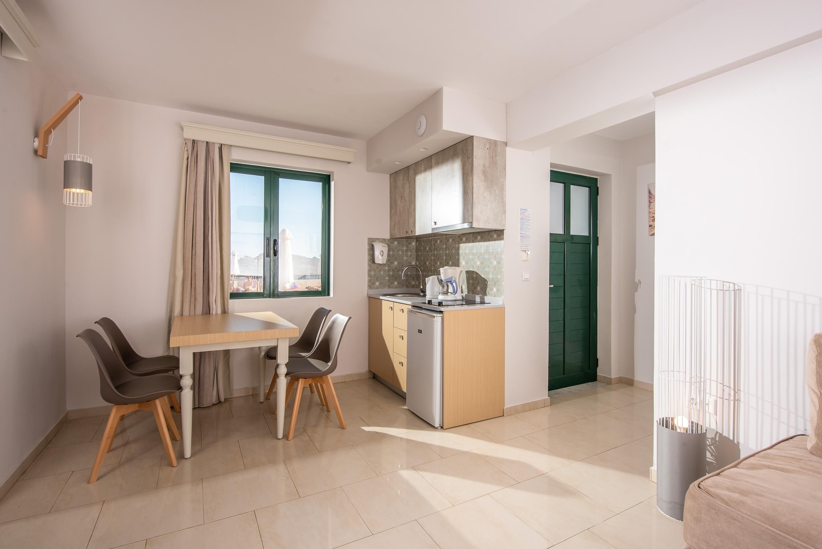 A compact kitchen with a dining area, a built-in dishwasher, and a view through the window.