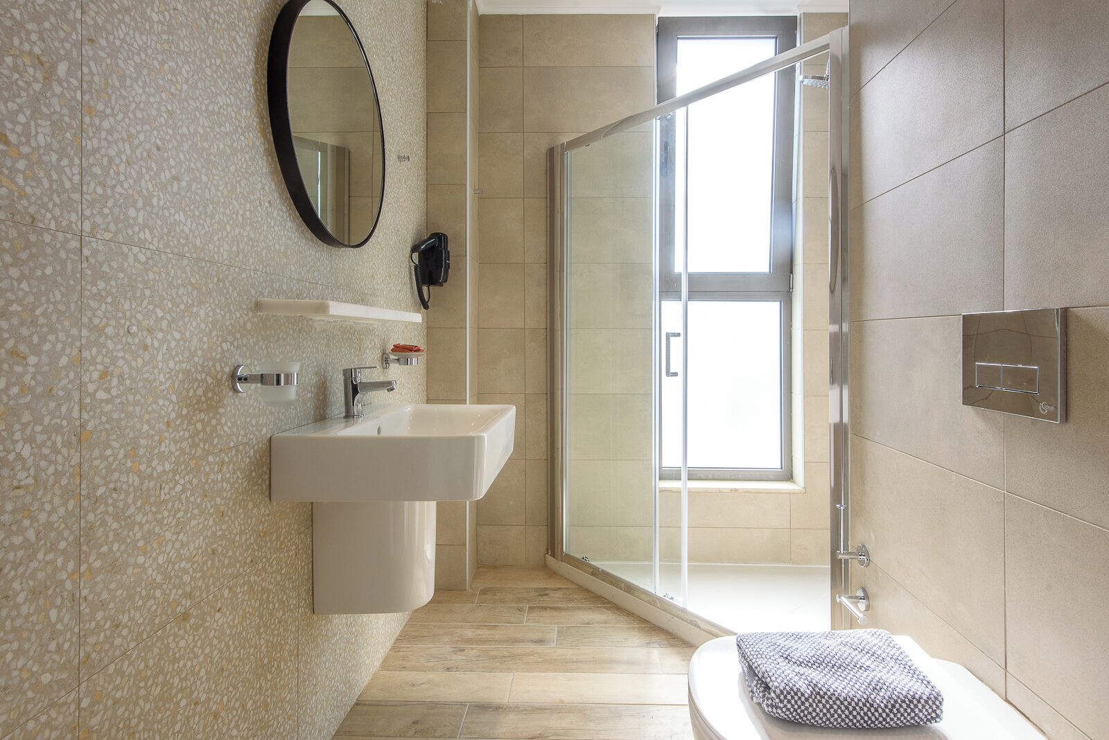 Un baño moderno con un lavamanos independiente, un espejo, una ducha con puerta de cristal y un inodoro.