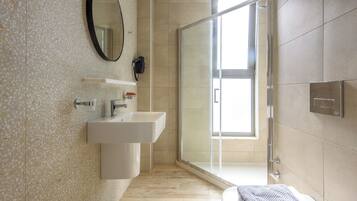 A modern bathroom with a freestanding sink, a mirror, a shower with a glass door, and a toilet.
