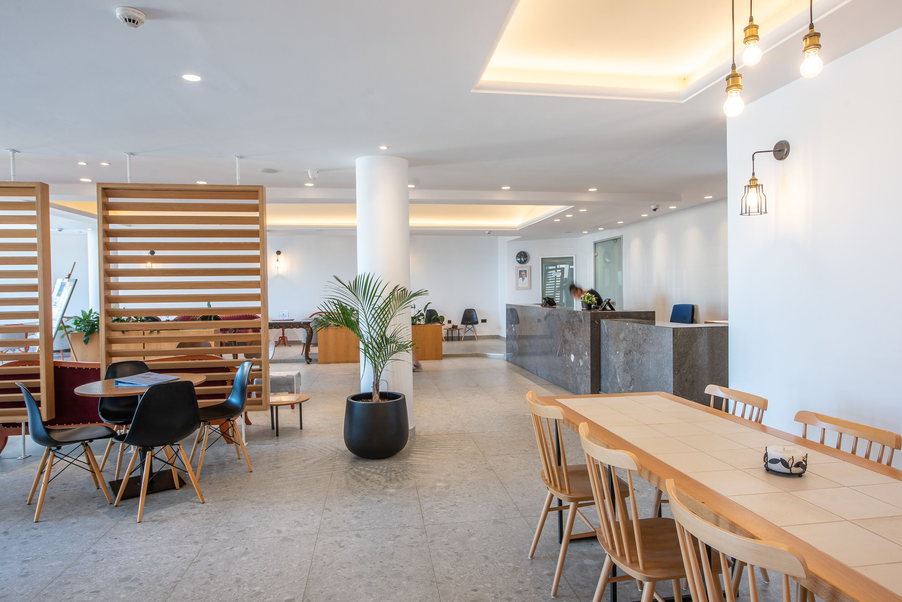 A spacious lobby with a reception desk, wooden partitions, and seating areas.