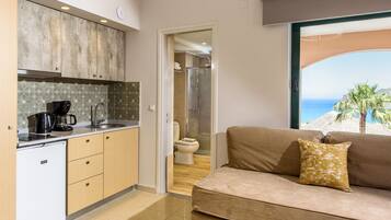 A compact kitchen with a coffee maker, a sink, and a shower area visible through an open door.