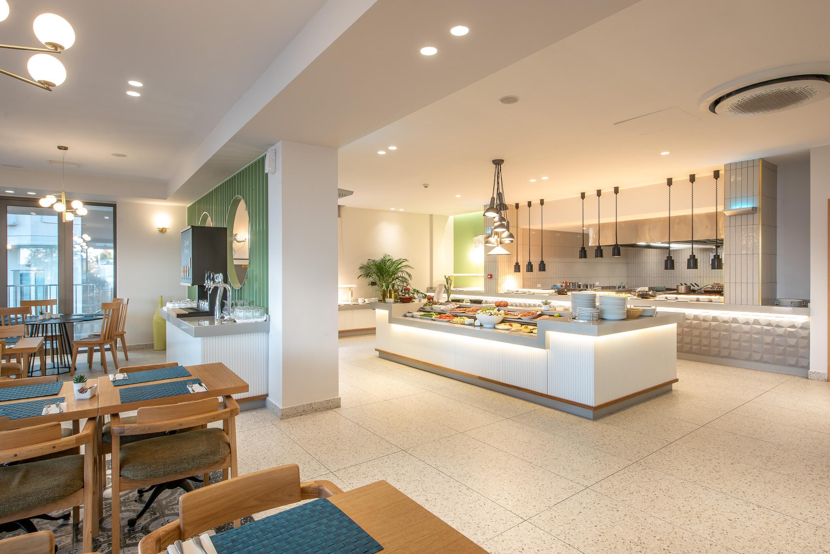 Une cuisine moderne dotée d’un îlot central, de luminaires suspendus et d’un coin repas avec des meubles en bois.