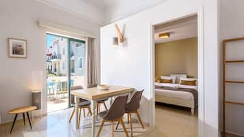 Ein modernes Hotelzimmer mit Essbereich, einem Bett mit Blick und einem Balkon mit Sitzgelegenheit.
