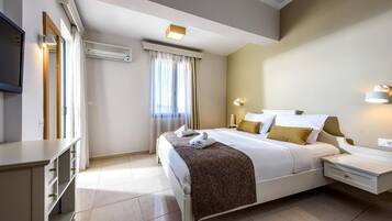 A hotel room with a bed, bedside tables, a TV, and an air conditioning unit.