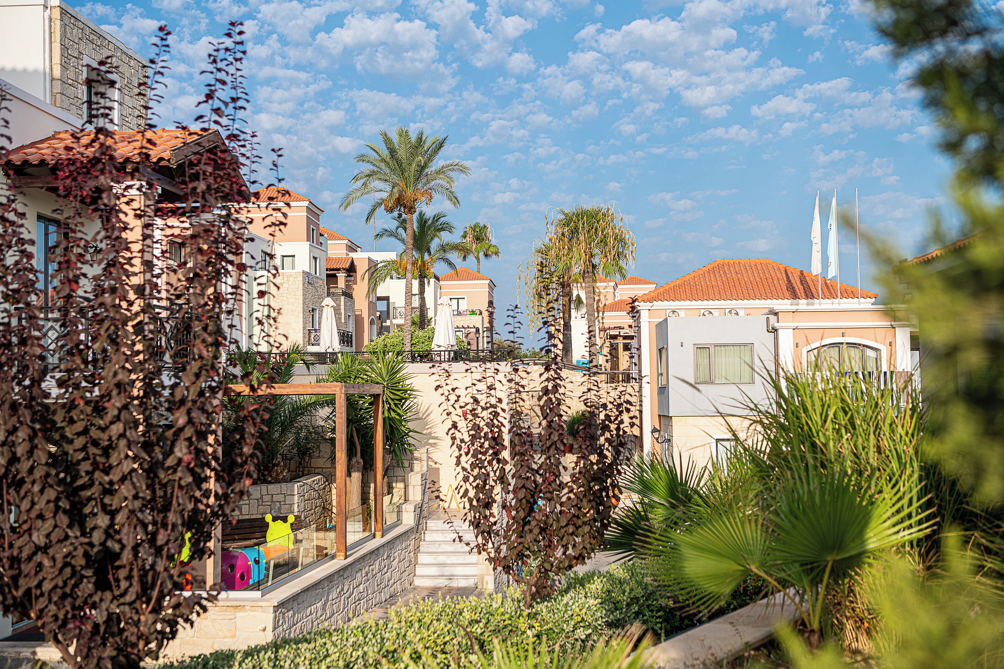 A residential area with a mix of modern and traditional architecture, featuring balconies, a stone pathway, and lush greenery.