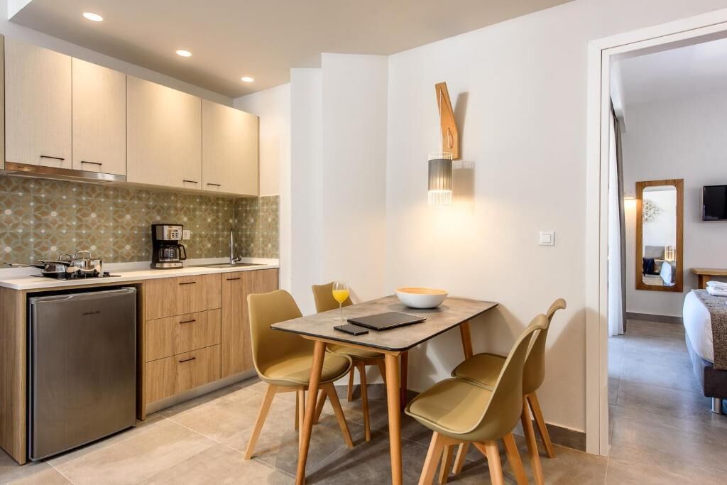 Een moderne keuken met een eethoek, inclusief een koelkast, kastjes en een eettafel met stoelen.