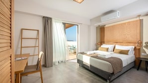 A hotel room with a bed, a desk, a chair, a window with curtains, and an air conditioning unit. - Caldera Village (Chania)