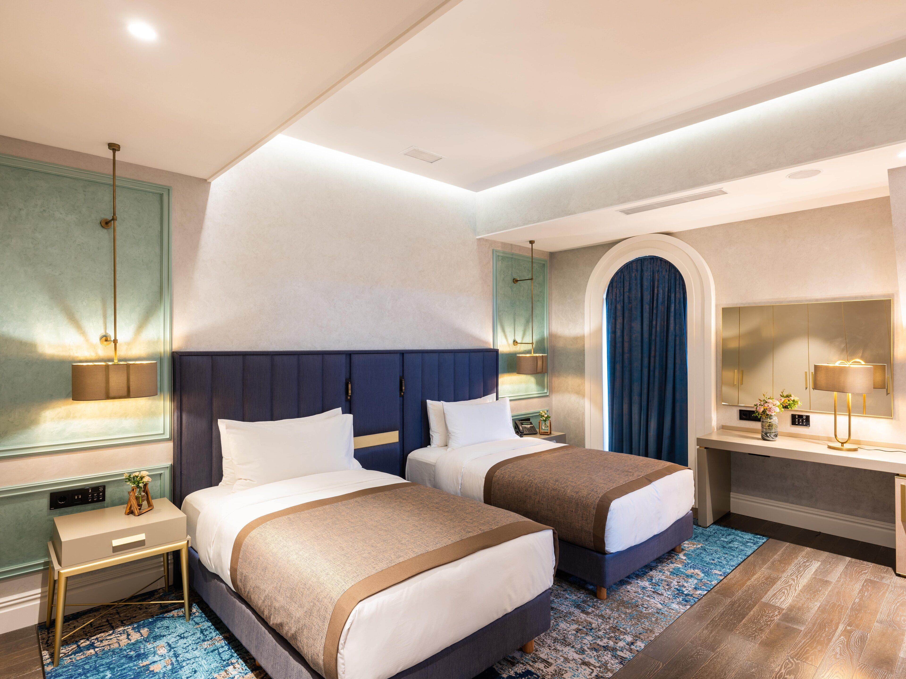 Een hotelkamer met twee bedden, een bureau, een stoel, een spiegel en een badkamer.