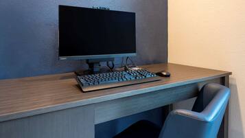 A modern office desk with a computer monitor, keyboard, and mouse.