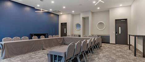 A conference room with a long table, chairs, and a carpeted floor.