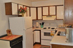 A compact kitchen with white appliances, wooden cabinets, and a small countertop.