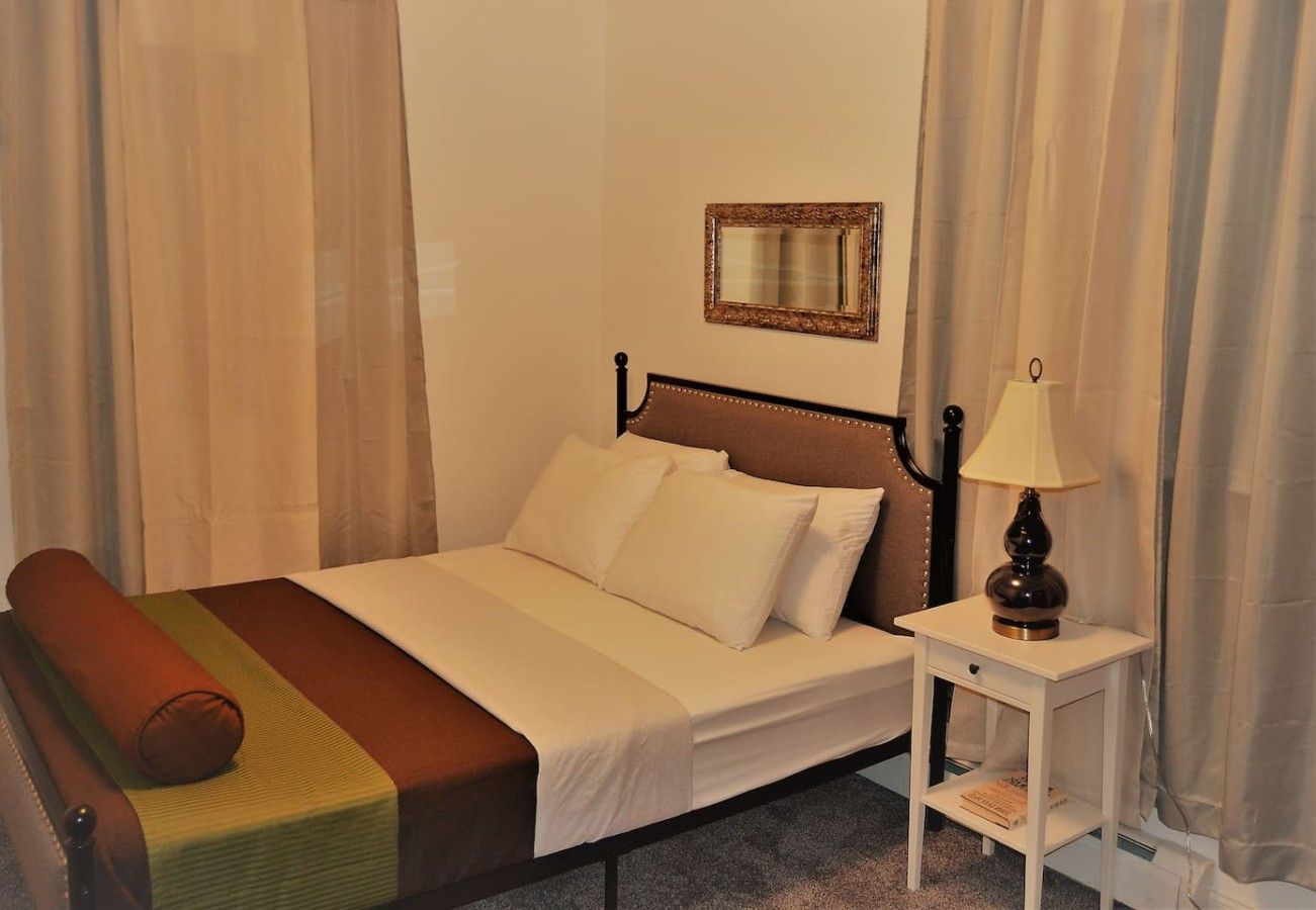 A single bed with a headboard, a bedside table with a lamp, and a mirror on the wall.