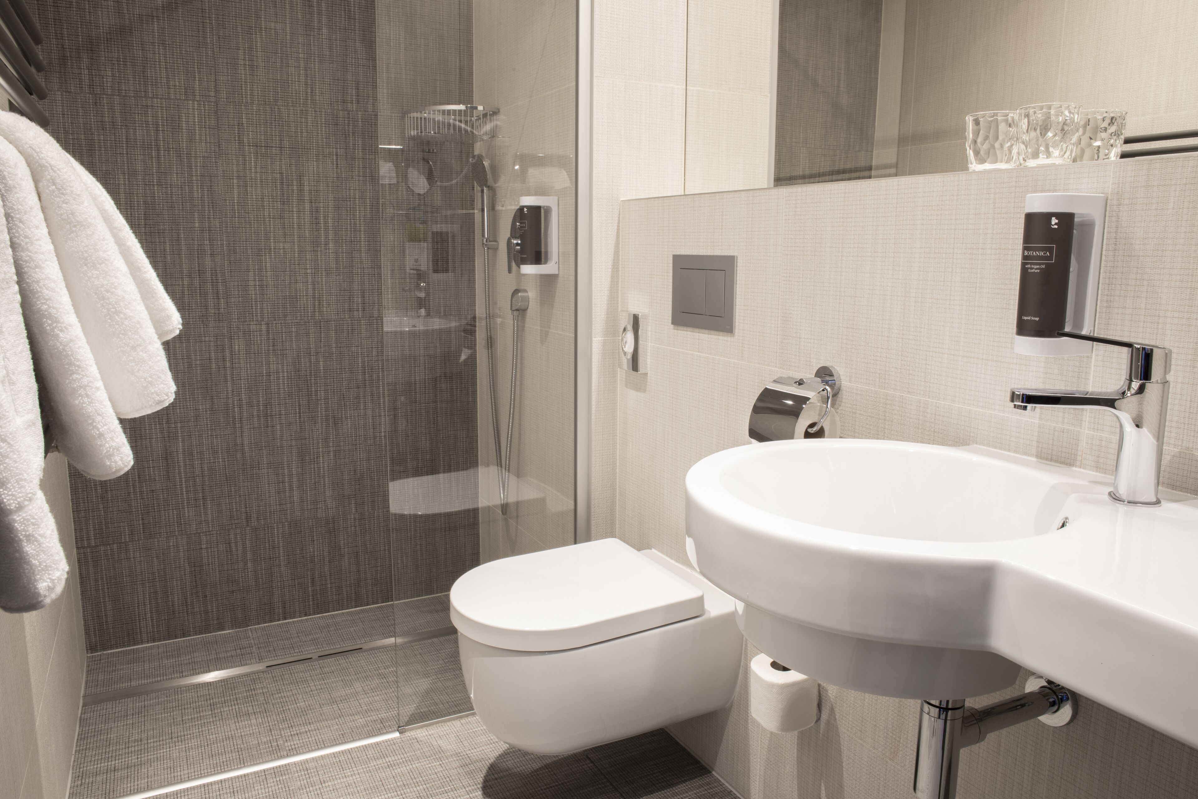 A modern bathroom with a glass-enclosed shower, a white toilet, and a sink with a mirror above it.
