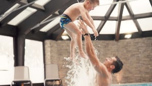 Un hombre y un niño jugando en una piscina, con agua salpicando a su alrededor.