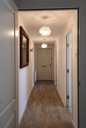 Stunning hallway with ornate chandelier, mirror, and modern door.
