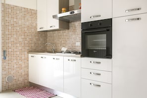 Eine moderne Küche mit weißen Schränken, einer Edelstahl-Dunstabzugshaube und einem schwarzen Backofen.