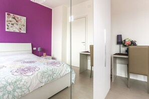 Ein modernes Hotelzimmer mit einem großen Bett, einem Schreibtisch und einem Sessel.
