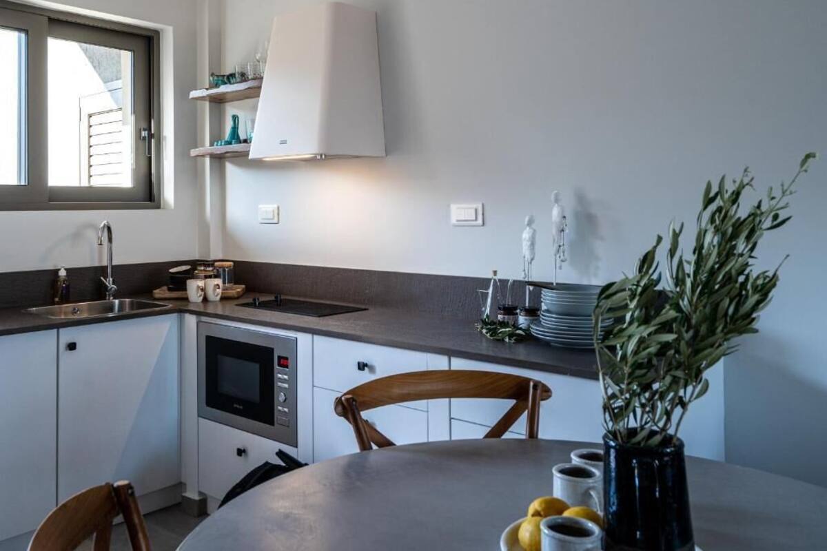 A compact kitchen with a built-in oven, a sink, and a dining area with a table and chairs.