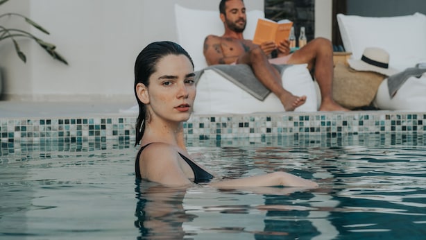 A pool area with a person in the foreground and another person reading a book in the background. - Pignolia Suites - Adults Only (Ierapetra)