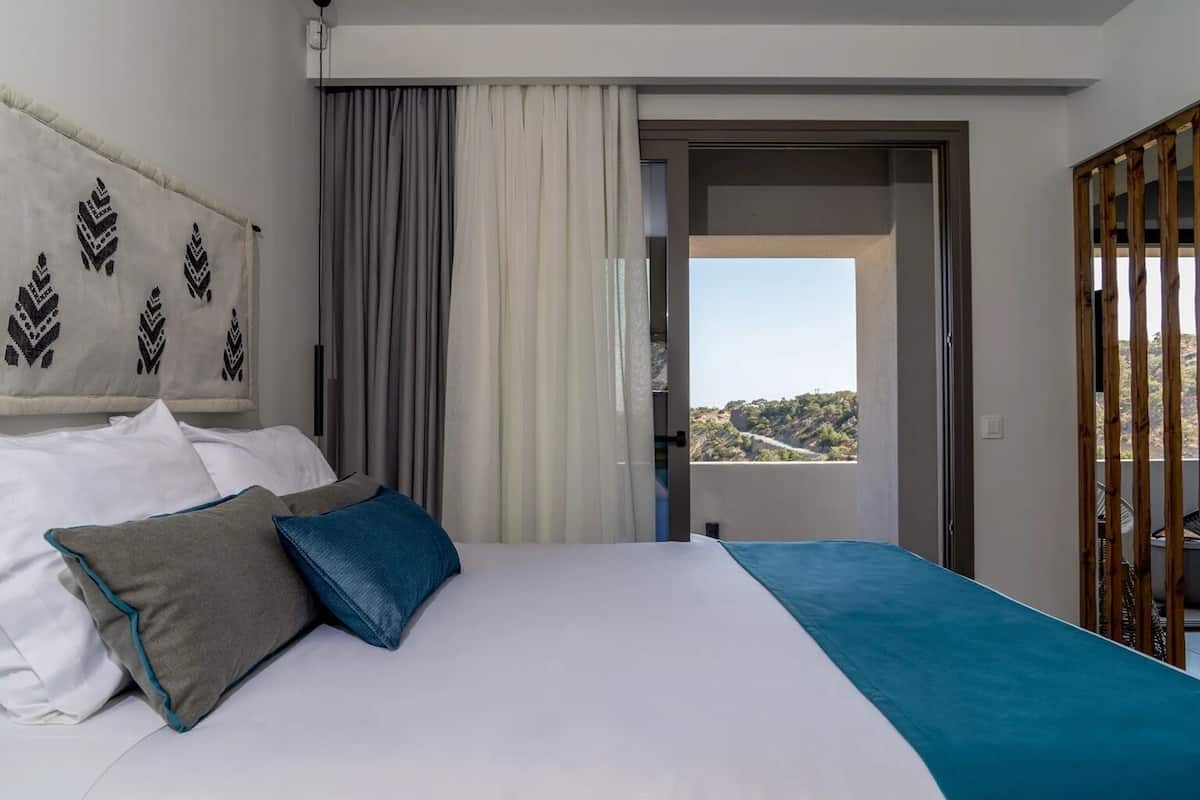 A hotel room with a bed, a view of the outdoors, and a balcony.