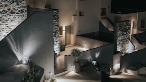 A modern building with a stone facade, multiple levels, and outdoor lighting. - Pignolia Suites - Adults Only (Ierapetra)